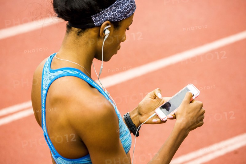 Black woman on track listening to cell phone with earbuds