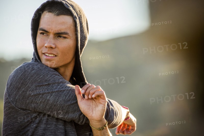 Serious Mixed Race man stretching arms