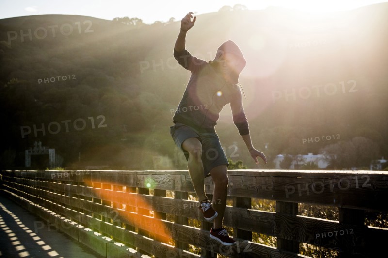 Mixed Race man jumping near railing on footbridge