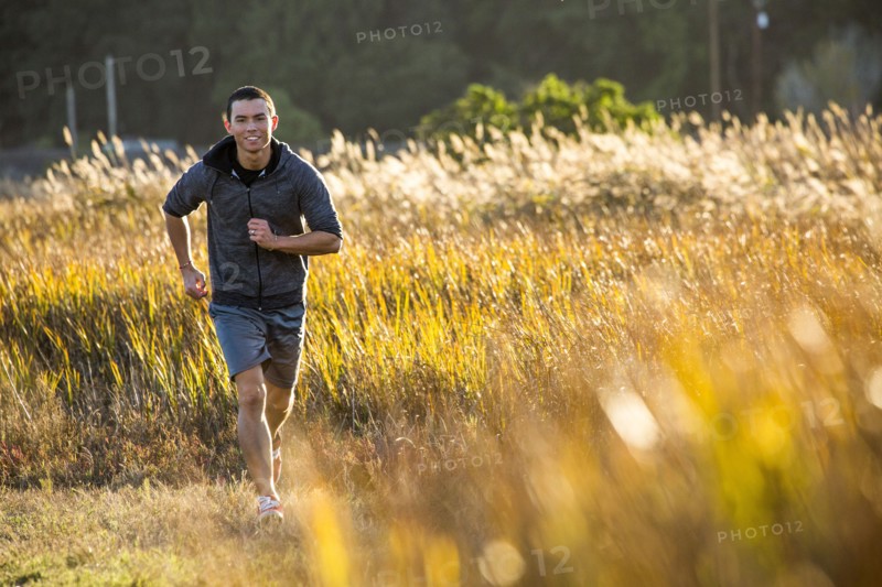 Smiling Mixed Race man running in field