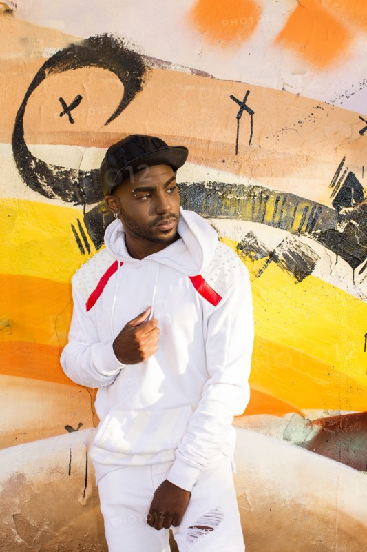 Serious Black man leaning on graffiti wall