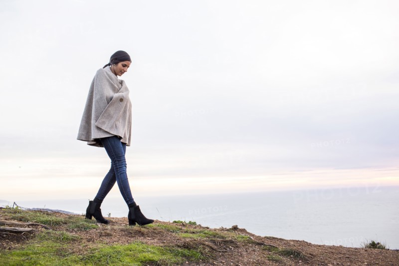 Indian woman wearing poncho walking on hill
