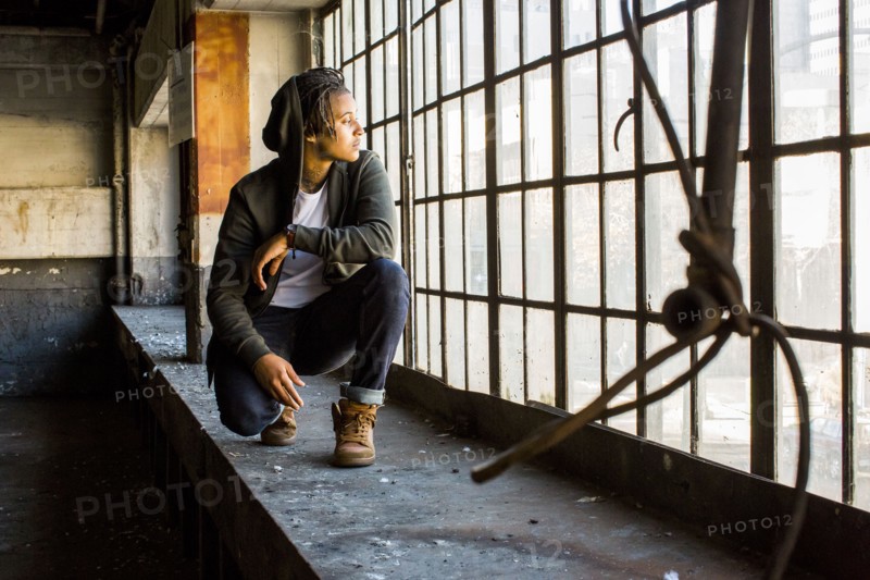 Androgynous Mixed Race woman crouching near window