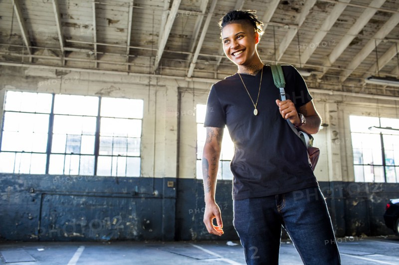 Smiling androgynous Mixed Race woman carrying backpack