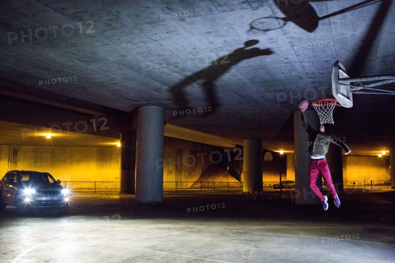 Headlights shining on Black man dunking basketball