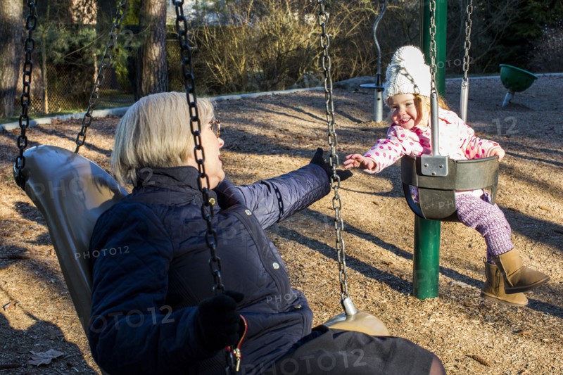 Caucasian grandmother and granddaughter on swings