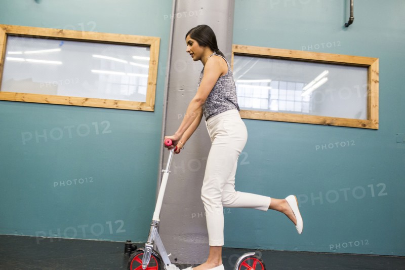 Asian woman riding scooter indoors