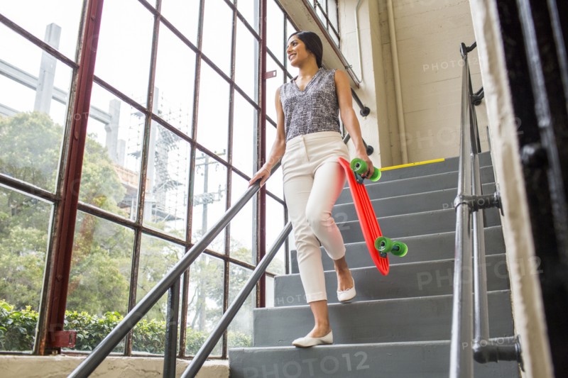 Asian woman carrying skateboard on staircase