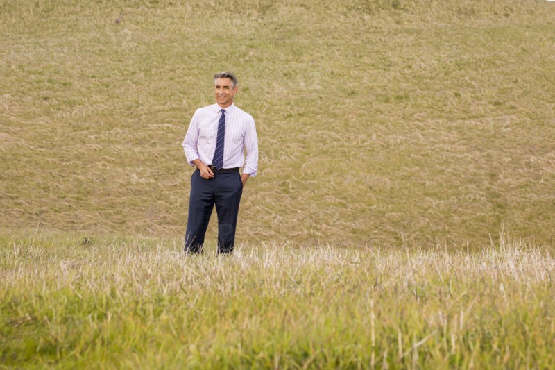 Smiling Caucasian businessman standing in grass