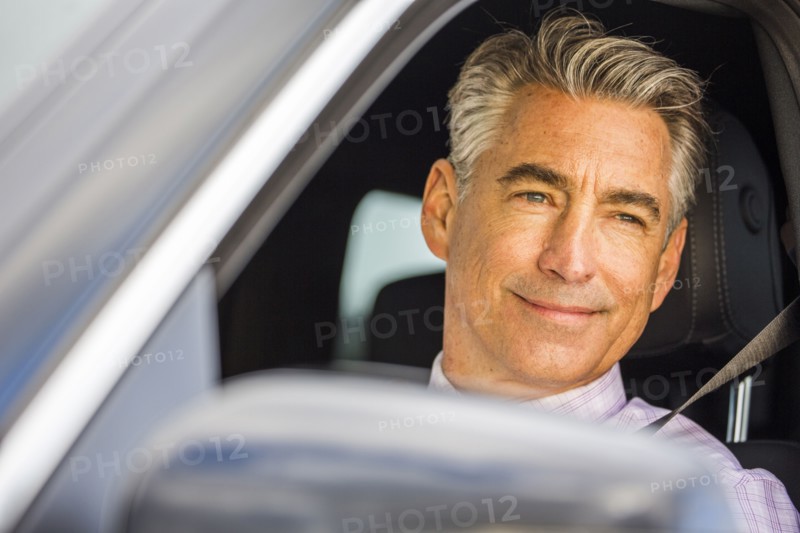 Smiling Caucasian businessman driving car