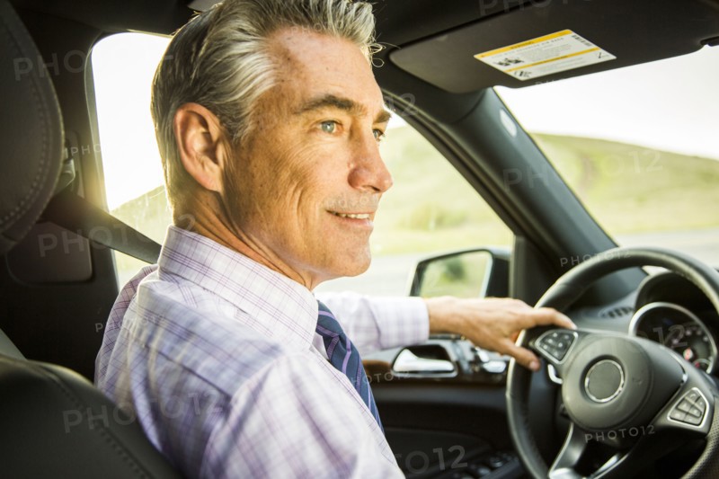 Smiling Caucasian businessman driving car
