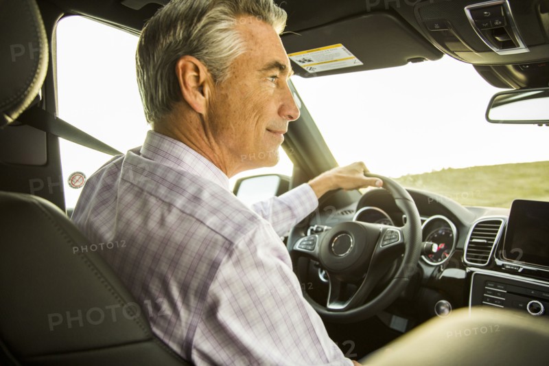 Smiling Caucasian businessman driving car