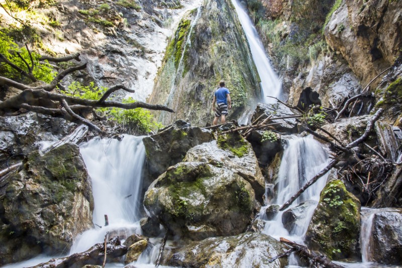 Caucasian man standing on rocks watching waterfall