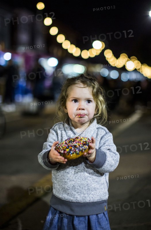 Caucasian girl eating donut outdoors at night