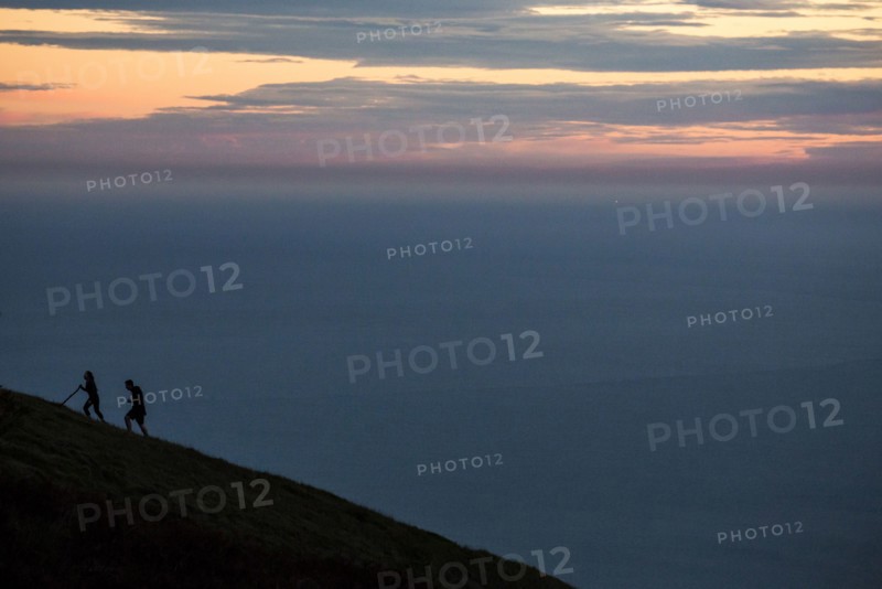 Hikers climbing hill at sunset