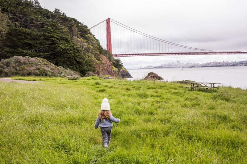 Caucasian girl walking in grass near bridge