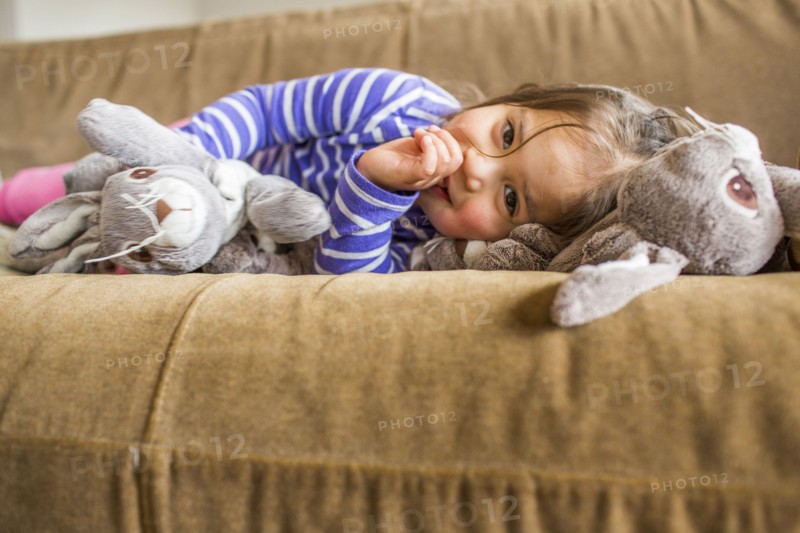 Caucasian girl laying on sofa sucking thumb