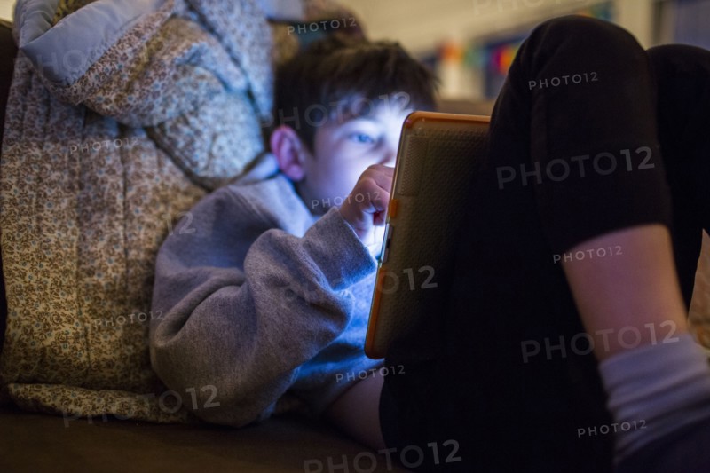 Mixed Race boy using digital tablet at night