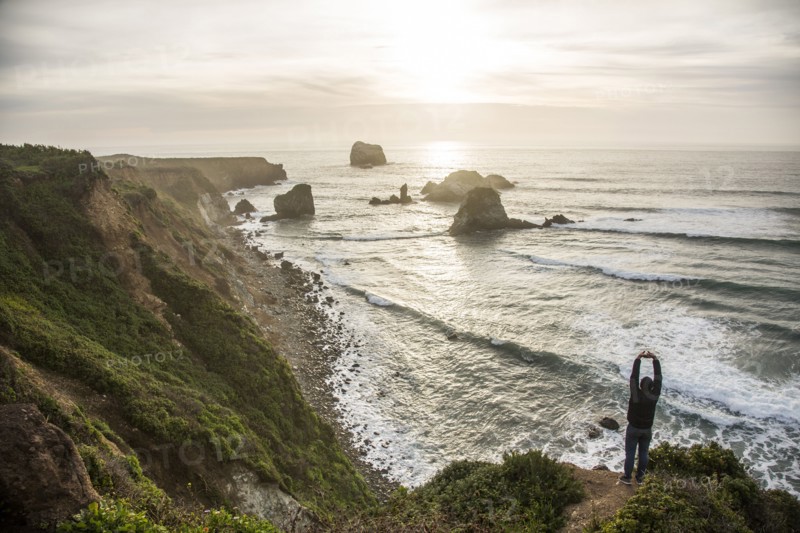 Caucasian man admiring scenic view of ocean sunset stretching arms