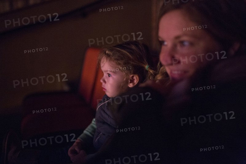 Caucasian mother and daughter watching movie in theater