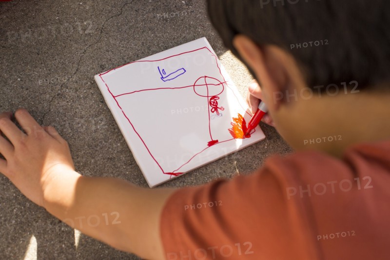 Mixed Race boy drawing on paper with marker