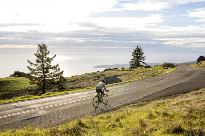 Caucasian man riding bicycle on road near ocean