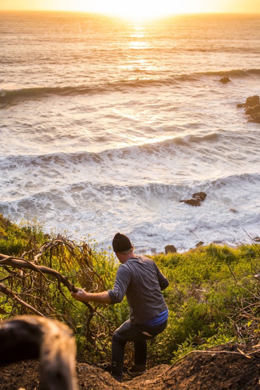 Caucasian man descending hill near ocean at sunset
