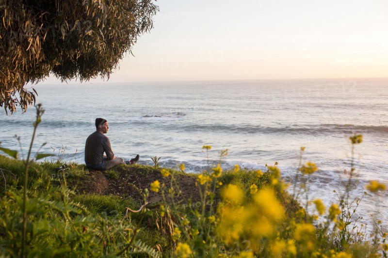 Caucasian man admiring scenic view of ocean at sunset