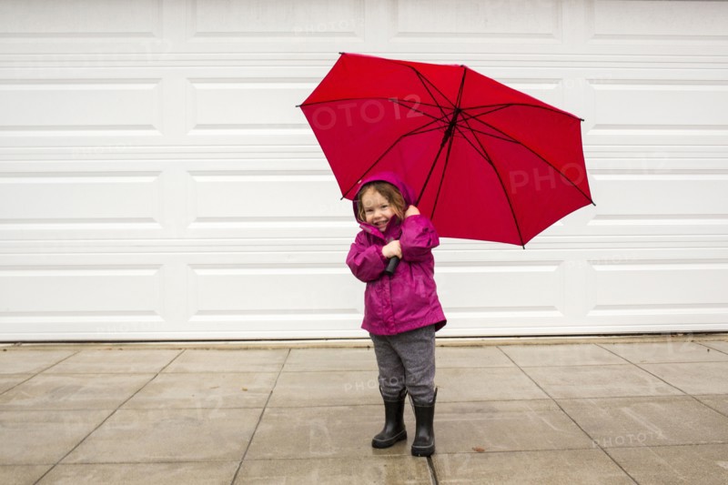 Caucasian girl holding red umbrella in wind