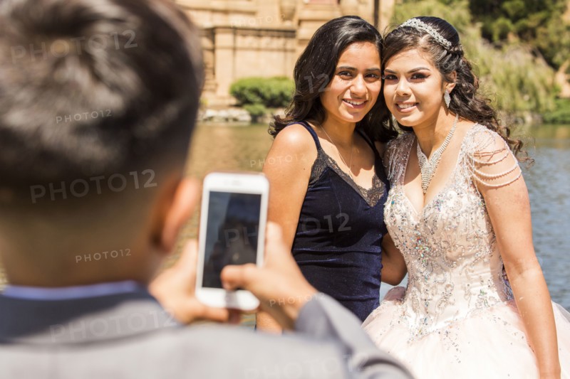 Hispanic boy photographing girls with cell phone
