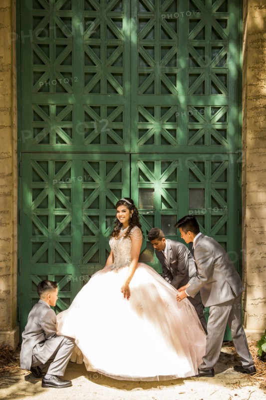 Hispanic boys wearing suits holding skirt of girl