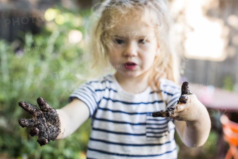 Caucasian girl with muddy hands in garden