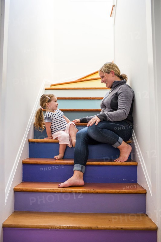 Caucasian mother and daughter laughing on multicolor staircase