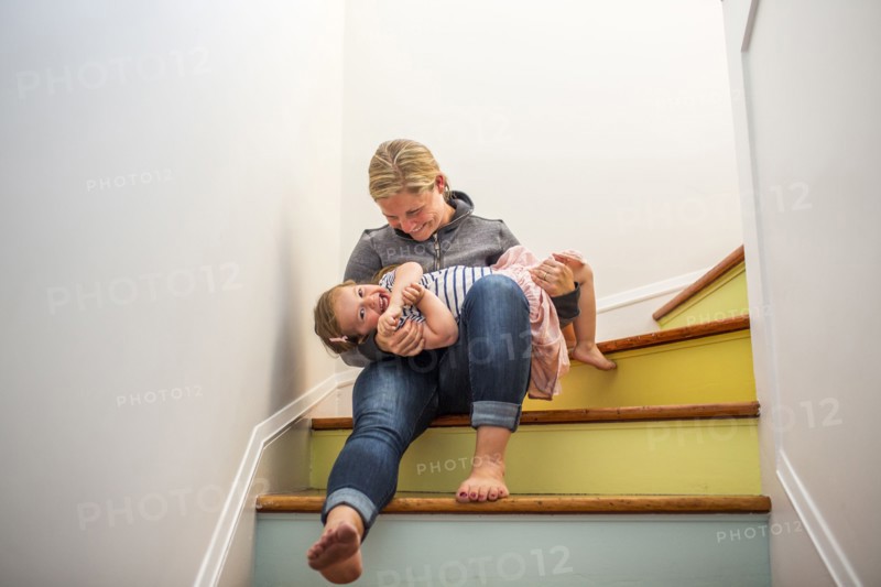 Caucasian mother and daughter playing on multicolor staircase