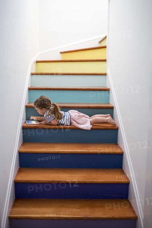 Caucasian girl using digital tablet on multicolor staircase