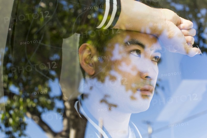 Serious Chinese man leaning on window