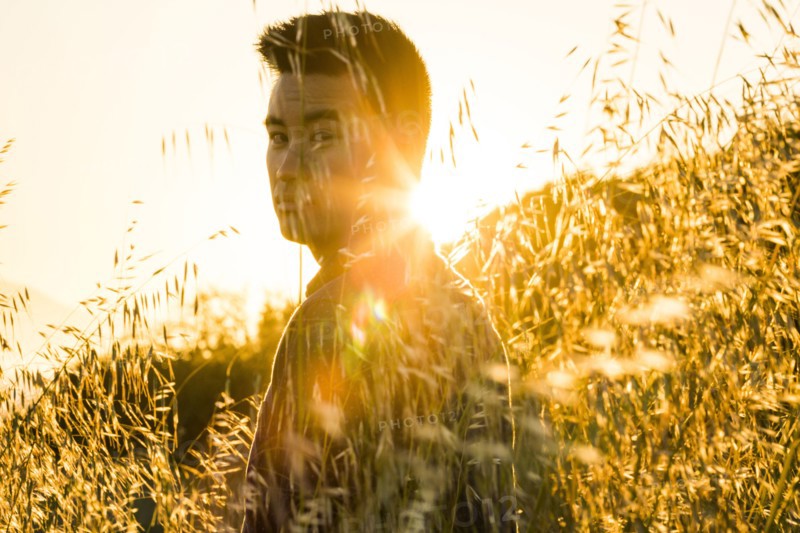 Serious Chinese man standing in field of wheat