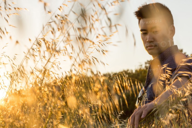 Serious Chinese man sitting in field of wheat