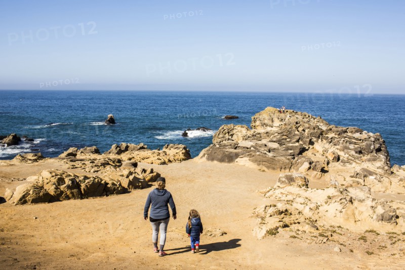 Caucasian mother and daughter walking near ocean