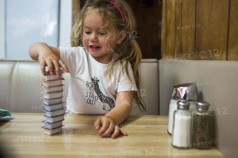 Smiling Caucasian girl stacking jelly containers in restaurant booth