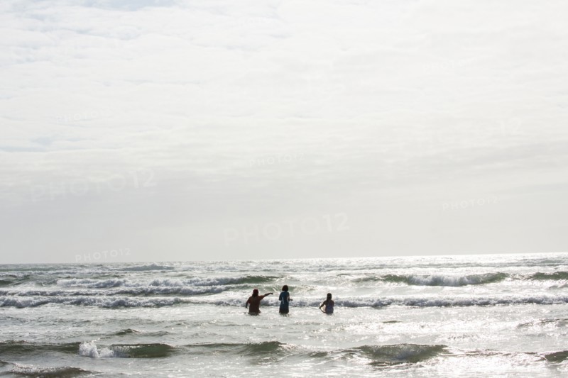 Caucasian people wading in ocean waves