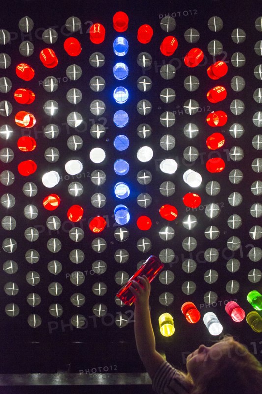Caucasian girl placing colorful game pieces on puzzle wall