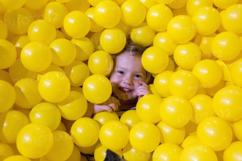 Caucasian girl laying in pile of yellow balls