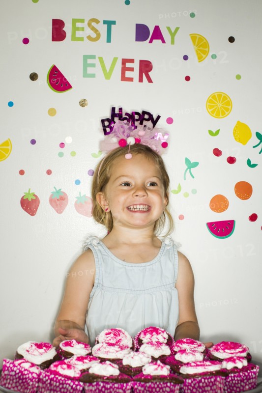 Caucasian girl holding tray of cupcakes for birthday