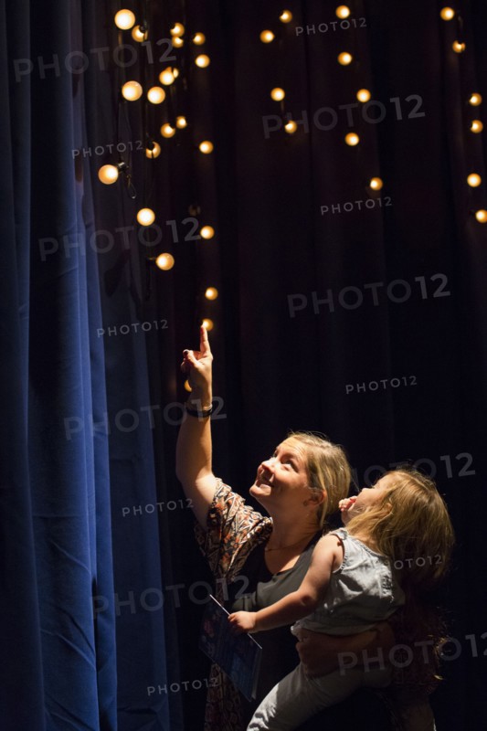 Caucasian mother and daughter looking up at blue curtain