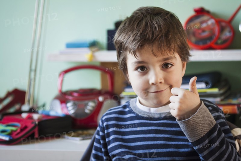 Caucasian boy giving thumbs up at desk