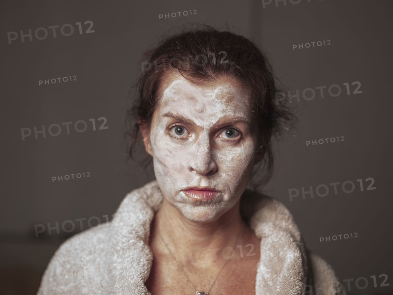 Caucasian woman wearing face cream and bathrobe