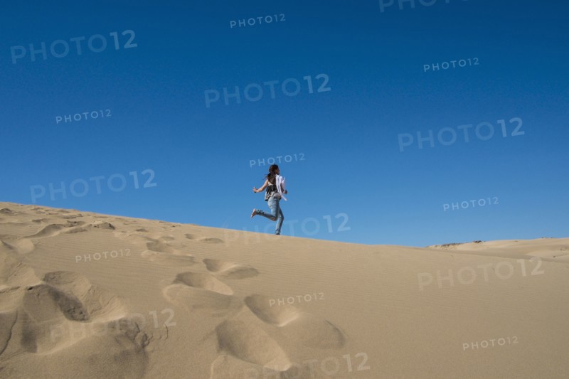 Caucasian woman running on sand dune