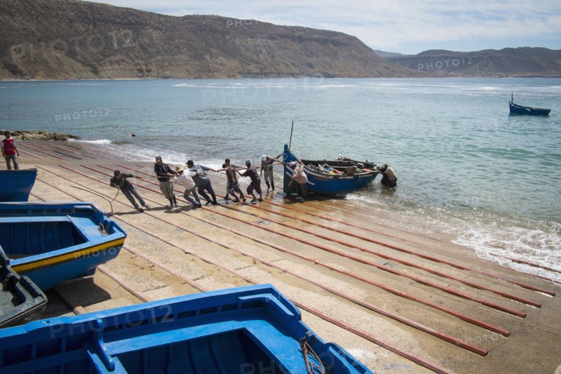 People pulling boat onto boat ramp