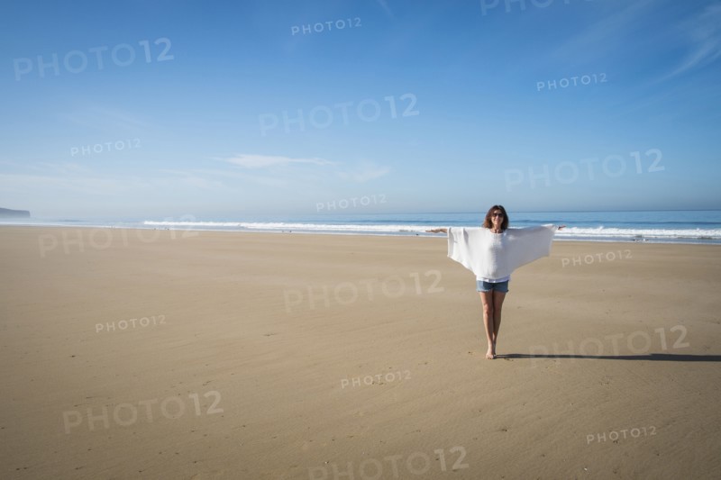 Caucasian woman walking on beach under blue sky